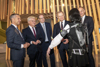 Landesrat Dr. Wolfgang Hattmannsdorfer, MMag. Klaus Luger, Dr. Stefan Koch, Landeshauptmann Mag. Thomas Stelzer und Christian Mader stehen nebeneinander in einem Ausstellungsraum des Ars Electronica Centers und betrachten ein von einer jungen Frau getragenes Exoskelett