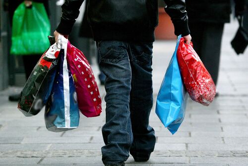 Ein auf der Straße gehender Mann, der fünf Plastiksackerl trägt