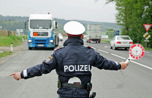 Ein Polizist hält auf einer Bundesstraße einen LKW auf