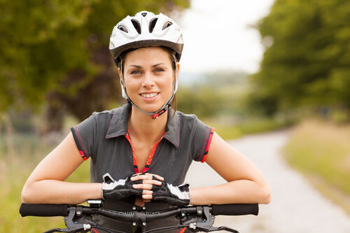 Eine Frau mit Fahrradhelm und Fahrradhandschuhen sitzt auf dem Fahrrad.