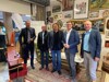 Fred Edlinger, Dr. Alfred Grausgruber, Mag. Martin Zwicker, Landesrat Stefan Kaineder und DI Thomas Anderer stehen nebeneinander im ReVital-Café Kreisler*in in der Tabakfabrik, Geschäftlokal, Bilder und verschiedene Gegenstände an der Wand, schöne alte Möbel