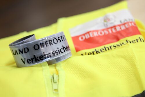 Reflektorband mit der Aufschrift „Verkehrssicherheit Land OÖ“ auf einer gelben Warnweste liegend