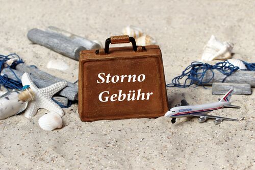 Koffer mit der Aufschrift Stornogebühr, Strand, Muscheln, Seestern, Flugzeug