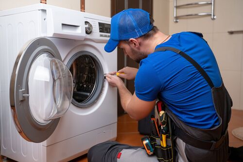 Mann in Arbeitskleidung repariert eine Waschmaschine 