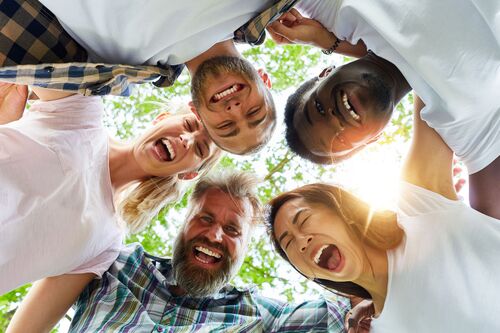 Menschen verschiedener Nationalitäten beugen sich lachend über eine Kamera