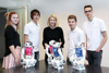 LH-Stellvertreterin Mag.a Christine Haberlander mit einer Schülerin und drei Schülern an einem Tisch, auf dem vier kleine menschenähnliche Roboter stehen
