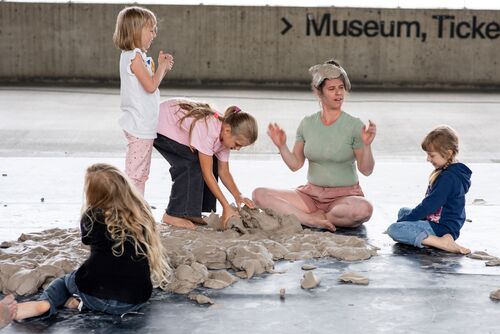 Motiv aus „Clay Play“, einem der Stücke des Theaterfestivals, junge Frau und Kinder spielen mit Ton.