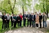 Eine Gruppe von 14 Personen, die nebeneinander stehen, auf einem gekiesten Weg in einem Park