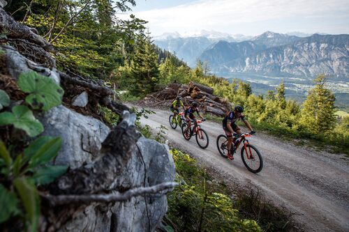 Drei Radsportler auf einem Schotterweg, Berge, See