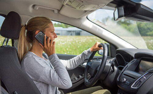 Eine junge Frau telefoniert während des Autofahrens.