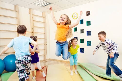 Kinder turnen neben einer Sprossenwand auf Matten