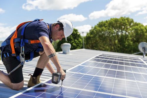 Arbeiter montiert Photovoltaikanlage auf Hausdach