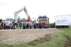 mehrere Personen – darunter  LR Markus Achleitner, LR Mag. Günther Steinkellner und Hörschings Bürgermeister Klaus Wahlmüller - stehen nebeneinander hinter einem Hügel mit Sand und jeweils mit einem Spaten in der Hand; hinter ihnen sind mehrere Baufahrzeuge zu sehen