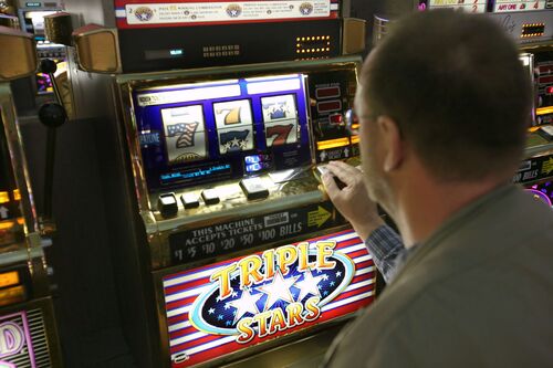 Mann sitzt vor Glücksspielautomaten und spielt