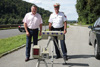 Landesrat Mag. Günther Steinkellner und Oberst Klaus Scherleitner stehen nebeneinander auf einem Parkplatz neben einer Straße, vor ihnen zwei verschiedene Radar-Messgeräte.