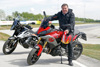 Landesrat Mag. Günther Steinkellner sitzt auf einem geparkten Motorrad im Hintergrund ein weiteres geparktes Motorrad, großes Übungsgelände für Sicherheitstraining