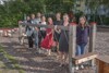 Acht Personen, zwei junge Männer und sechs junge Frauen, stehen lächelnd hintereinander bei einem Spielgerät zum Balancieren auf einem Spielplatz 