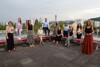 Zehn Frauen und ein Mann stehen oder sitzen im Abstand nebeneinander auf einer Dachterrasse , im Hintergrund Aussicht auf Häuser und Bäume