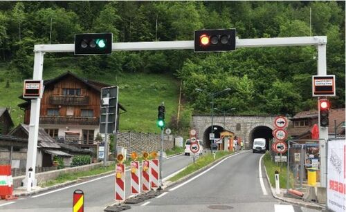 Fahrbahnsanierung vor dem Tunnel von Hallstatt  - Straße, Ampelanlage, zwei Autos und ein Wohnhaus neben der Straße dahinter Wald