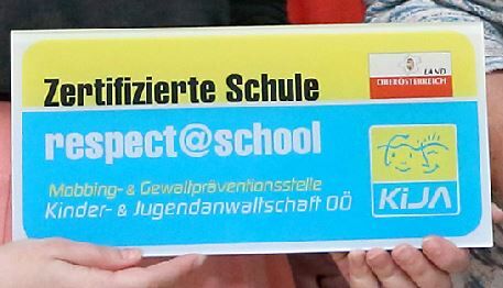 Hände halten eine Tafel mit der Aufschrift Zertifizierte Schule -  respect@school 