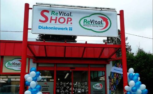 Geschäftsfront, Eingangsbereich, darüber ein Schild mit Beschriftung ReVital.Shop., Logo mit Beschriftung ReVital.Ökologisch.Günstig.Sozial.