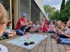 Kinder und ein Naturführer sitzen im Kreis um eine Weltkarte, auf der zwei Kakaobohnen liegen