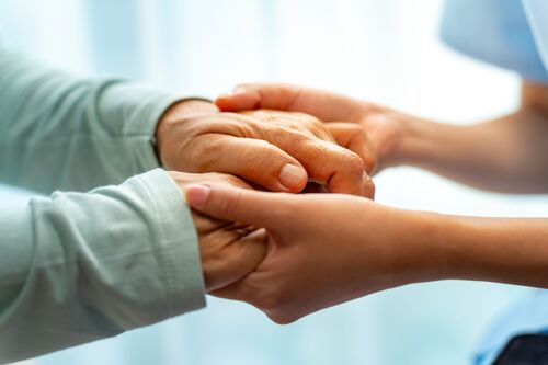 Hände einer Pflegekraft halten die Hände einer anderen Person