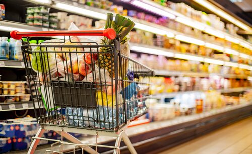 Einkaufswagen vor einem Lebensmittelregal in einem Supermarkt