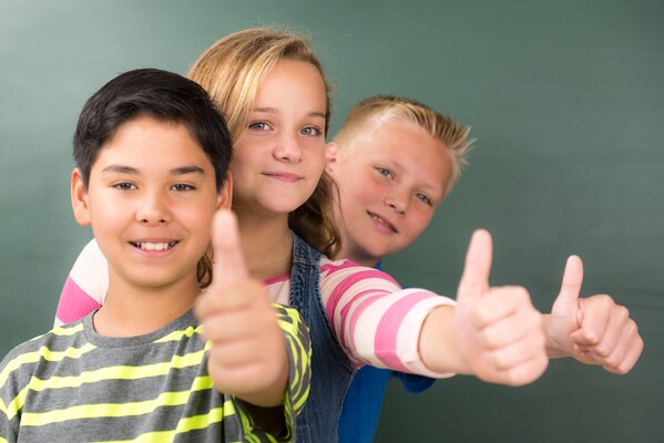 Drei Kinder vor einer Schultafel deuten ok