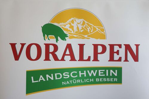 Plakat mit der Aufschrift „Voralpenlandschwein – natürlich besser“, Schwein vor einem Berg
