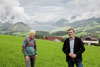 Christine Zauner und Klima-Landesrat Stefan Kaineder auf einer Wiese, im Hintergrund Berge und Häuser.