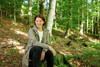 Forst-Landesrätin Michaela Langer-Weninger sitzend auf einem Baumstumpf in einem Wald.