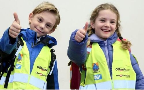 Mädchen und Bub mit Warnwesten deuten OK