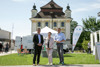 Der Trauner Bürgermeister Ing. Karl-Heinz Koll, Umwelt- und Klima-Landesrat Stefan Kaineder und die Abteilungsleiterin der Abt. Wasserwirtschaft, Dipl. Ing. Daniela König MBA stehen im Freien nebeneinander vor dem Schloss Traun, im Hintergrund Kleinbus der Trinkwasserwirtschaft, Wiesenstück, Stühle, Fahnen mit der Aufschrift „Trinkwasserwirtschaft“