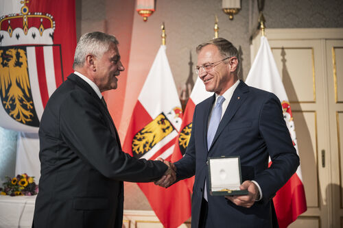 Landeshauptmann Thomas Stelzer überreicht Landesamtsdirektor Erich Watzl das Goldene Ehrenzeichen des Landes Oberösterreich.