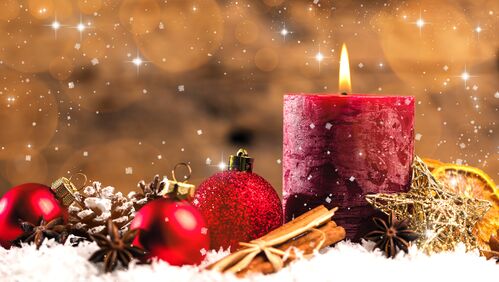 Brennende Kerze umrahmt mit weihnachtlicher Dekoration