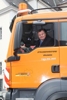 LR Steinkellner am Steuer eines orangen Lastkraftwagens einer Straßenmeisterei.