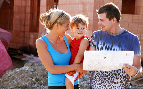 Eine Familie studiert vor dem Rohbau den Wohnungsplan.