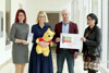 Mag.a Marlene Fehringer, LH-Stv.in Mag.a Christine Haberlander, Mag. Martin Hajart, MBA und Elisabeth Zehetner, MA ECED stehen nebeneinander am Gang des Presseclubs und halten einen Teddybären ein Schild und eine Broschüre in den Händen.