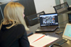 Landeshauptmann-Stellvertreterin Mag.a Christine Haberlander sitzt bei einem Online-Meeting an einem Schreibtisch, vor ihr ein Bildschirm, auf dem Portraits von zwanzig Personen zu sehen sind