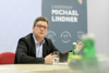 Landesrat Michael Lindner sitzt an einem Besprechungstisch, im Hintergrund Rollup des Landesrates