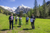 Landeshauptmann Mag. Thomas Stelzer, Landesrat Max Hiegelsberger, Johanna Ellmauer, Helmut Immitzer und Johann Fessl auf einer Almwiese, im Hintergrund Wald und hohe schneebedeckte Berge