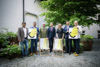 Mag. Gerhard Uttenthaler, Mario Hermüller mit Poster zur communale, Georg Adam Starhemberg, Landeshauptmann Mag. Thomas Stelzer, Mag.a Margot Nazzal, Christian Penn und Dr. Alfred Weidinger (mit Poster) stehen nebeneinander in einem Innenhof mit vielen Pflanzen, vor ihnen zwei Liegestühle mit Beschriftung communale oö