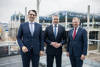 Milan Nedeljković (Produktionsvorstand der BMW AG), Bundeskanzler Karl Nehammer und Landeshauptmann Mag. Thomas Stelzer stehen nebeneinander vor einer im Bau befindlichen Produktionsanlage.