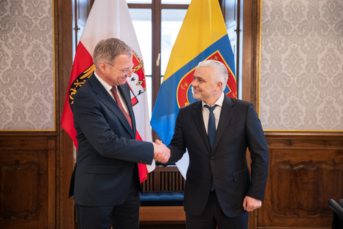 Landeshauptmann Thomas Stelzer und Gouverneur Oleg Kiper begrüßen einander; im Hintergrund die oberösterreichische Fahne und die Fahne von Odesa.