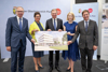 Mag. Dietbert Timmerer, MMag.a Bettina Schneebauer, Landeshauptmann Mag. Thomas Stelzer, LH-Stv.in Mag.a Christine Haberlander und Dr. Andreas Rabl stehen vor einem OÖ Plakatwand nebeneinander und halten ein Rendering des geplanten Neubaus am Klinikum Wels-Grieskirchen in Händen