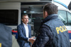 Landesrat Dr. Wolfgang Hattmannsdorfer begrüßt einen Polizeibeamten, im Hintergrund ein Polizei-Einsatzfahrzeug 