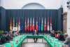 Menschen an einem Konferenztisch mit Vorsitz Landeshauptmann Thomas Stelzer, im Hintergrund Bühne mit Fahnen der Bundesländer