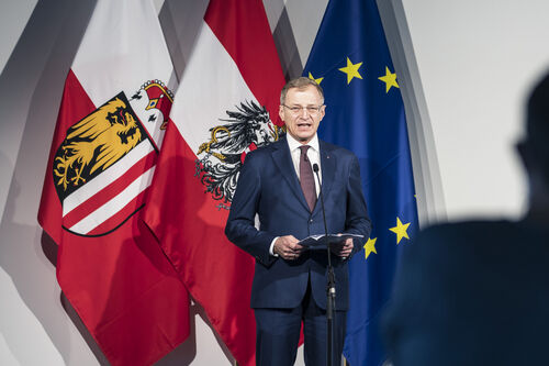Landeshauptmann Thomas Stelzer am Mikrofon, im Hintergrund die Oberösterreich-, Österreich- und EU-Fahnen.
