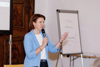 Landesrätin Michaela Langer-Weninger in der Halbtotalen mit einem Mikrophon in der Hand. Daneben steht ein Flipchart.